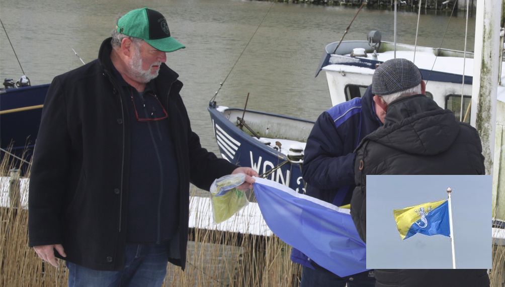 Voorzitter Henk Bonthuis van de Stichting Âld Makkum overhandigt de speciale vlag