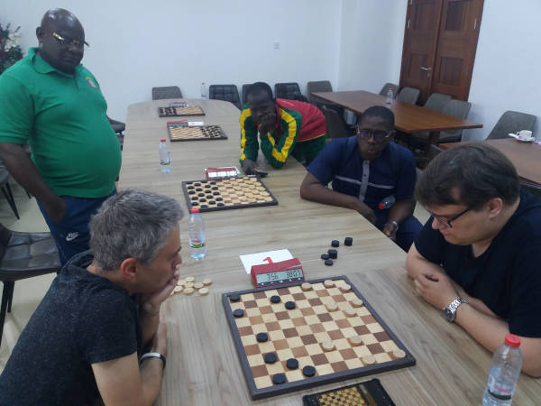 Foto WFD: Aleksej Domchev (l) in de laatste fase van zijn partij tegen Jan van Dijk. Ndjofang (l), Sayouba Kiema uit Burkino Faso en Eyock kijken gespannen toe